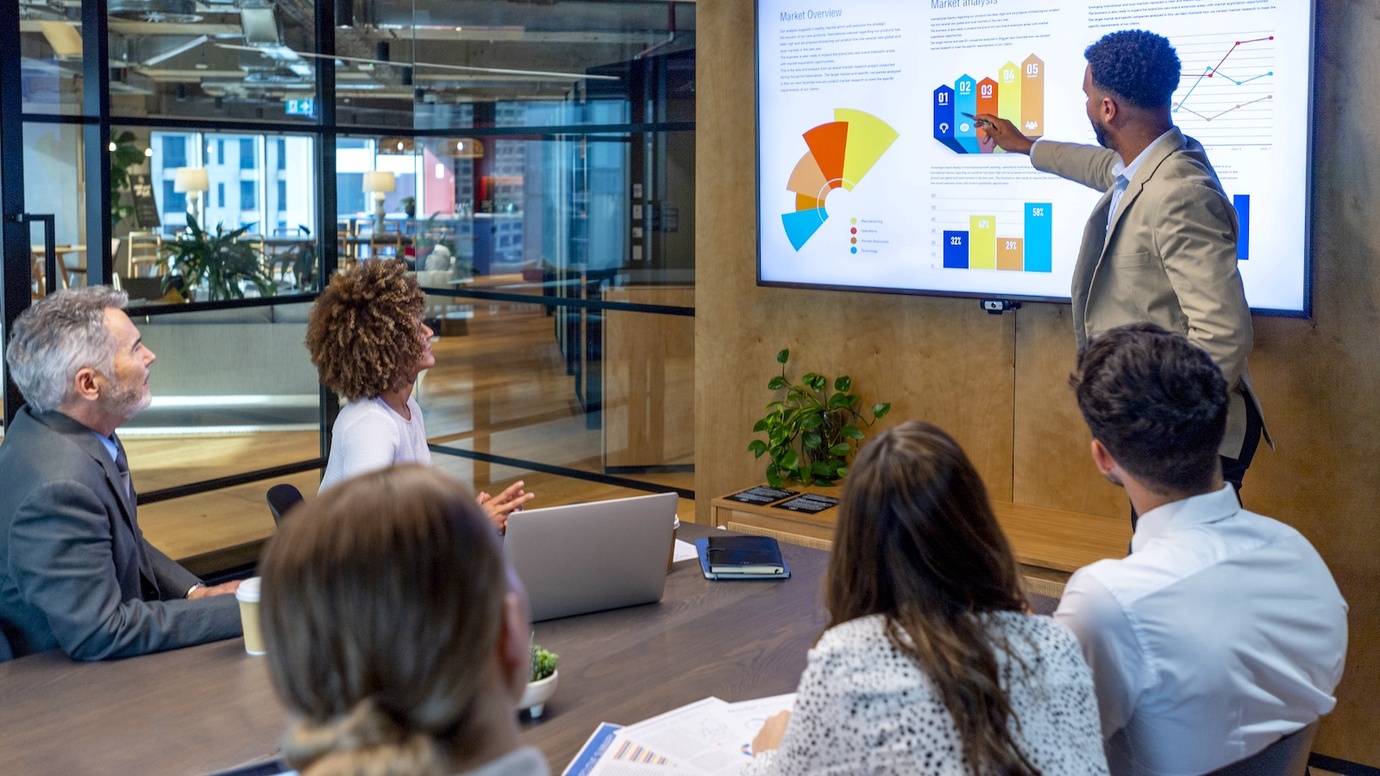 man is presenting with 5 people listening